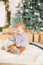 Cute little boy by the Christmas tree and fireplace decorated with garlands and gifts. Royalty Free Stock Photo