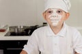 Cute little boy cook with a face full of flour