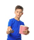 Cute little boy with cup of popcorn switching channels on white background Royalty Free Stock Photo