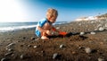 Cute little boy digging sand on the sea ocean beach and building sand castle Royalty Free Stock Photo