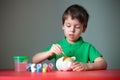 Cute little boy diligently painting his piggy toy