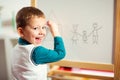 Cute little boy drawing on white board with felt pen and smiling Royalty Free Stock Photo