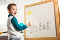 Cute little boy drawing on white board with felt pen and smiling Royalty Free Stock Photo