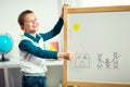 Cute little boy drawing on white board with felt pen and smiling Royalty Free Stock Photo