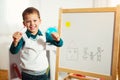 Cute little boy drawing on white board with felt pen and smiling