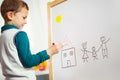 Cute little boy drawing on white board with felt pen and smiling Royalty Free Stock Photo