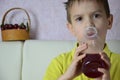 Cute little boy drinking juice at home, cherry juice drinks from a bottle or a glass with a straw. Royalty Free Stock Photo