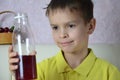 Cute little boy drinking juice at home, cherry juice drinks from a bottle or a glass with a straw. Royalty Free Stock Photo