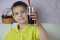 Cute little boy drinking juice at home, cherry juice drinks from a bottle or a glass with a straw. Royalty Free Stock Photo