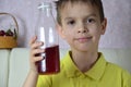 Cute little boy drinking juice at home, cherry juice drinks from a bottle or a glass with a straw. Royalty Free Stock Photo