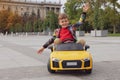 Cute little boy driving children`s car on city street Royalty Free Stock Photo