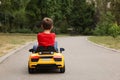 Cute little boy driving children`s car outdoors, back view. Space for text Royalty Free Stock Photo