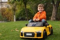 Cute little boy driving children`s car in park. Space for text Royalty Free Stock Photo
