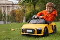 Cute little boy driving children`s car in park. Space for text Royalty Free Stock Photo