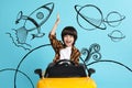 Cute little boy driving toy car and drawing of space on light blue background Royalty Free Stock Photo