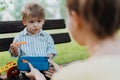 Cute little boy eating chopped carrots from lunch box, sitting on a park bench.