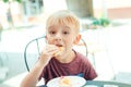 Cute little boy eating cookie outdoor on cafe terrace. Royalty Free Stock Photo