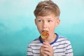 Cute little boy eating lollipop on color background Royalty Free Stock Photo