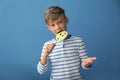 Cute little boy eating lollipop on color background Royalty Free Stock Photo