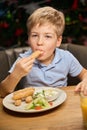 Cute little boy eating nuggets during New Year dinner in restaurant Royalty Free Stock Photo