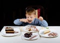 Cute little boy enjoying a treat of party cakes