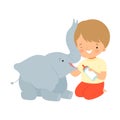 Cute Little Boy Feeding Baby Elephant with Milk Bottle, Adorable Kid Caring for Animal Cartoon Vector Illustration Royalty Free Stock Photo