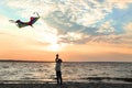 Cute little boy flying kite near river at sunset Royalty Free Stock Photo