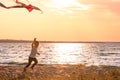 Cute little boy flying kite near river at sunset Royalty Free Stock Photo