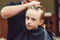 Cute little boy getting haircut by hairdresser at the barbershop Royalty Free Stock Photo