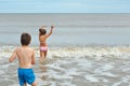 Cute little boy and girl, playing in wave on beach