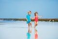 Cute little boy and girl run on sand beach over ocean hold hands Royalty Free Stock Photo