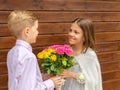 Cute little boy giving bouquet of flowers to charming little lady Ã¢â¬â smiling girl in love receiving yellow and pink roses Royalty Free Stock Photo