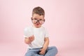 The cute little boy in glasses holds a light bulb, pink backgrund. Creative thinking concept.