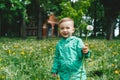 Cute little boy in green jacket on the meadow in summer day Royalty Free Stock Photo