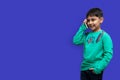 Cute little boy in a green shirt talking on the phone on a plain background with copy space