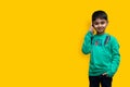 Cute little boy in a green shirt talking on the phone on a plain background with copy space