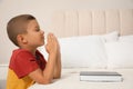 Cute little boy with hands clasped together saying bedtime prayer over Bible at home. Space for text Royalty Free Stock Photo