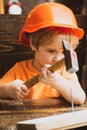 Cute little boy in hard hat holding wooden plank and hammer. Carpenter tools. Royalty Free Stock Photo