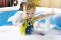 Cute little boy having fun playing with bubbles in an inflatable pool on a summer vacation Royalty Free Stock Photo