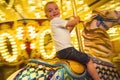 Happy little boy riding a merry go round carousel with bright lights Royalty Free Stock Photo