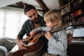 Cute little boy and his handsome father are playing guitar and smiling at home Royalty Free Stock Photo