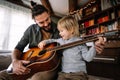 Cute little boy and his handsome father are playing guitar and smiling at home Royalty Free Stock Photo