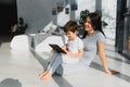 Cute little boy and his young mother using a digital tablet and smiling on the floor at home. Happy family with gadget Royalty Free Stock Photo