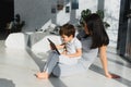 Cute little boy and his young mother using a digital tablet and smiling on the floor at home. Happy family with gadget Royalty Free Stock Photo