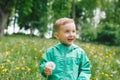 Cute little boy holding dandelion on meadow and looking aside Royalty Free Stock Photo