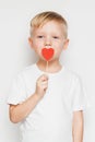 Cute little boy holding a heart shape sign against his lips