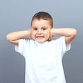 Cute little boy kid covering his ears with hands against gray background Royalty Free Stock Photo