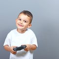 Cute little boy kid holding joystick and playing video games against gray background Royalty Free Stock Photo