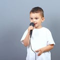 Cute little boy kid singing on microphone against gray background Royalty Free Stock Photo