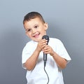 Cute little boy kid singing on microphone against gray background Royalty Free Stock Photo